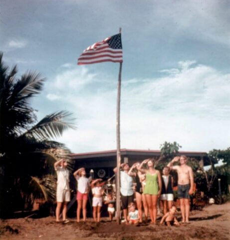 The Crockett family salute the US flag on the beach in front of the temporary US Embassy at San Juan Del Sur, Nicaragua, 1969. ©KMC