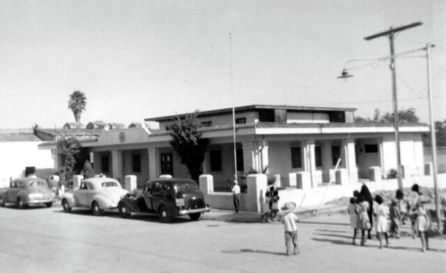 A one story buidling on a corner is the US Consulate, Nuevo Laredo, México, c 1944. Vehicles from the '30s and '40s are parked outside. ©KMC