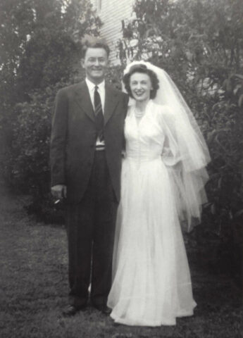 A young man in a suit and a young woman in a white wedding gown on their wedding day, September 8, 1943. ©KMC