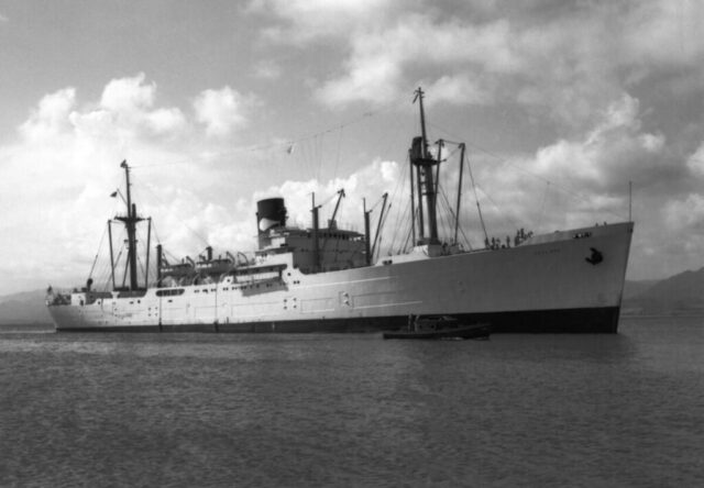 An enormous 'banana boat' ship called 'San José' with a tiny tug named 'Sula' in a harbor with mountains in the background, Puerto Cortes, Honduras, 1946. ©KMC