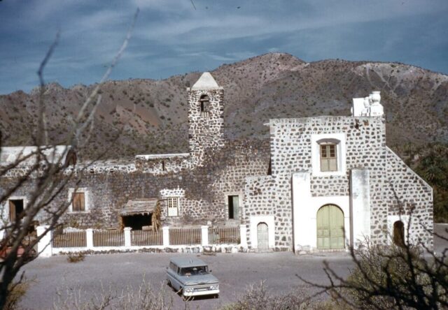 The ancient stone Misión Santa Rosalía de Mulegé with a desert mountain as a backdrop, Baja California Sur, México, 1961. ©KMC
