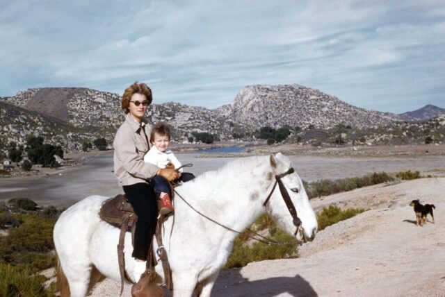 Seventeen-year-old Laura holds two-and-a-half-year-old Terry as they ride horseback among the rocky hills at Agua Hechicera Ranch, Baja California, 1962. ©KMC