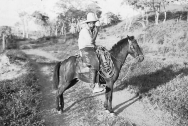 A campesino wearing a broad rimmed hat and riding a horse rests in the middle of a dirt trail in Honduras, 1946. ©KMC